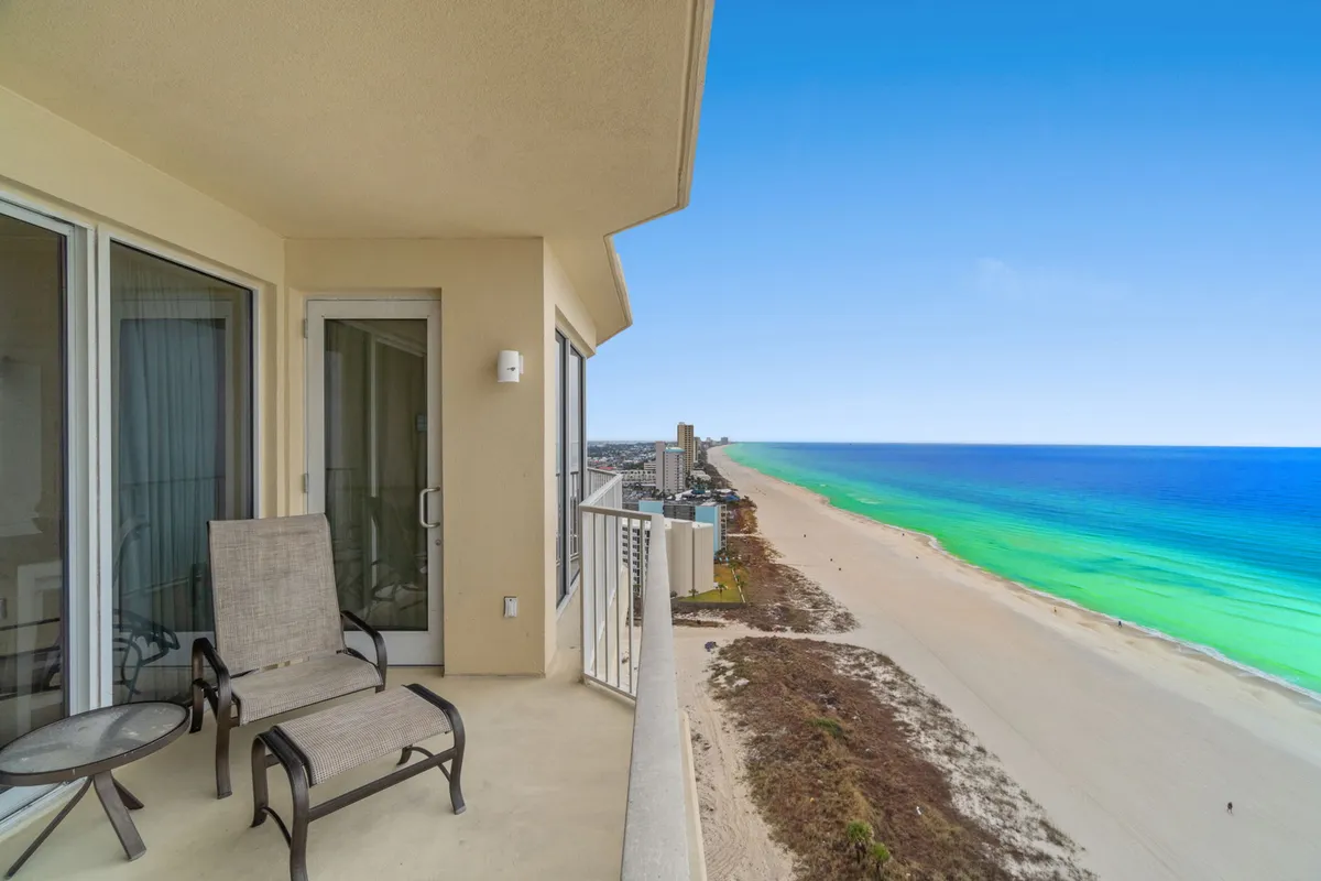 A serene balcony space overlooks the ocean, beach, and an expansive sky. There are chairs set up for relaxation, perfectly angled to enjoy both the sunrise and sunset, with a sense of privacy and intimacy ideal for couples.