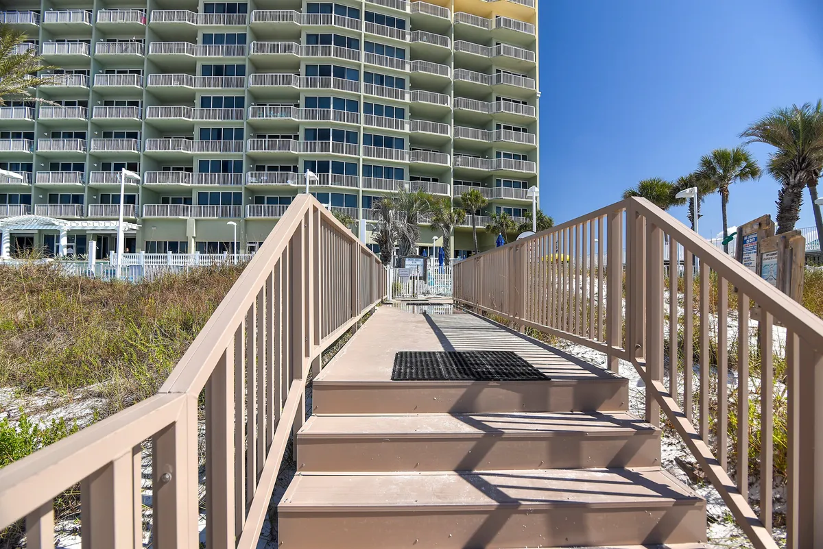 A gentle pathway lined with vegetation leads directly from the building to the sandy beach. The inviting scene hints at leisurely beachfront strolls and a seamless connection between the accommodation and the shoreline.